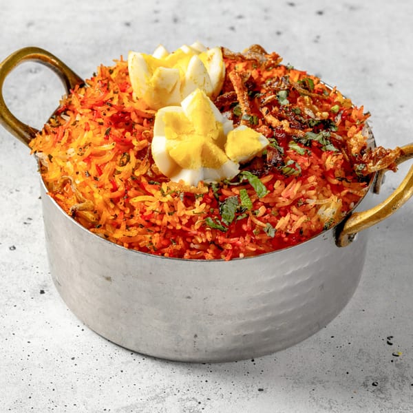 Nirvana Indian Kitchen's Egg Biryani, a vibrant rice dish with hard-boiled eggs, herbs, and fried onions.
