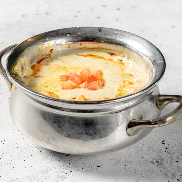 Creamy Indian dish with diced tomatoes in a silver pot, from Nirvana Indian Kitchen.