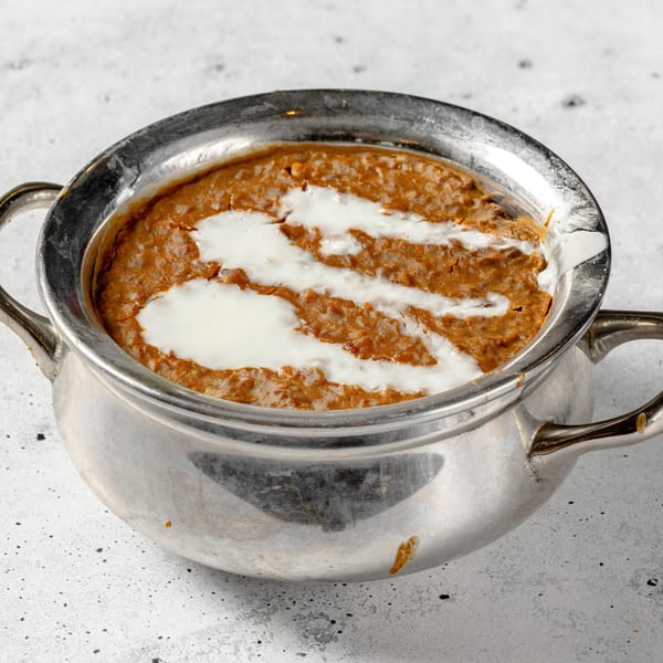 Nirvana Indian Kitchen's Dal Makhani, a rich lentil dish topped with cream, served in a silver bowl.