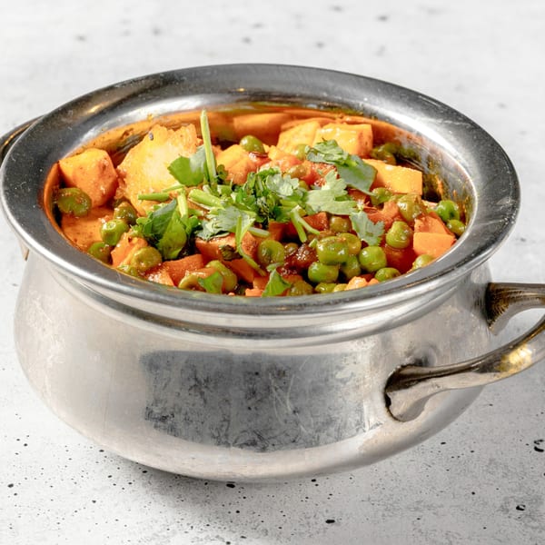 Aloo Matar, an Indian dish with potatoes and peas in a rich sauce, garnished with cilantro.