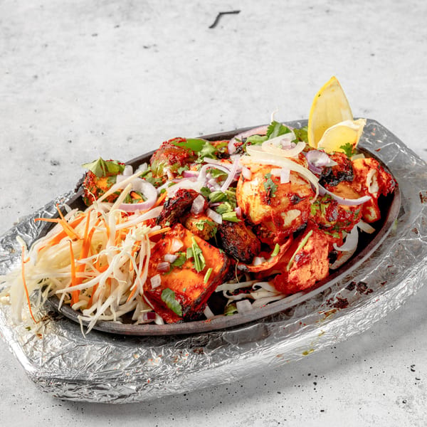 Nirvana Indian Kitchen's paneer tikka, garnished with onions, cilantro, and a lemon wedge.
