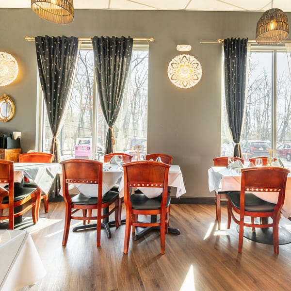Nirvana Indian Kitchen dining room with set tables, dark curtains, and decorative wall lights.